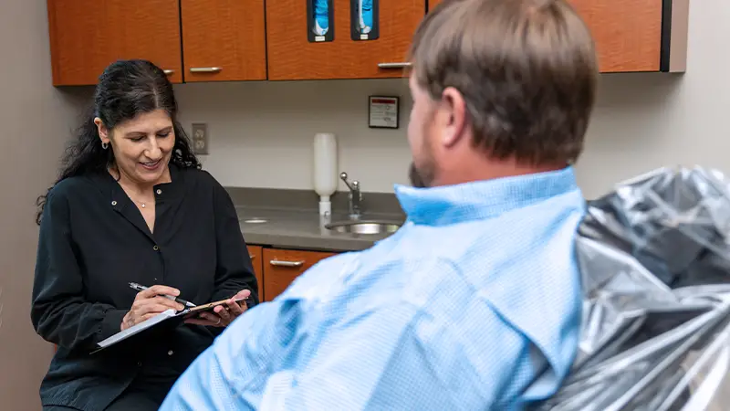 Hygienist taking notes while client explains emergency