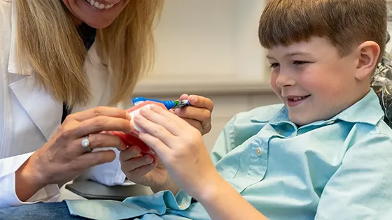 little boy looking at teeth model smiling